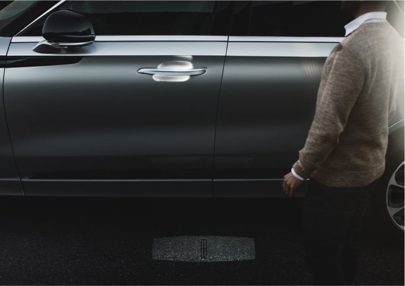 A person approaches a 2023 Lincoln Aviator® Grand Touring as the Lincoln Embrace sequence of welcome lighting illuminates | Mathews Lincoln in Marion OH