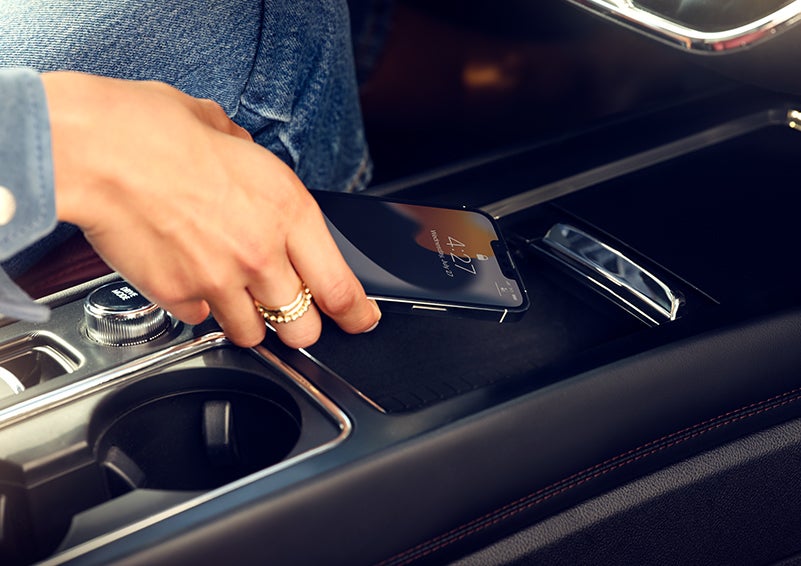 A smartphone is is being placed on the wireless charging pad in the front center console cubby. | Mathews Lincoln in Marion OH