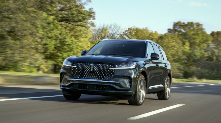 A 2025 Lincoln Black Label Aviator® SUV is being driven down a road lined with trees. | Mathews Lincoln in Marion OH