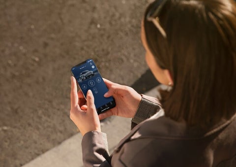 A person is shown interacting with a smartphone to connect to a Lincoln vehicle via the Lincoln Way® App. | Mathews Lincoln in Marion OH