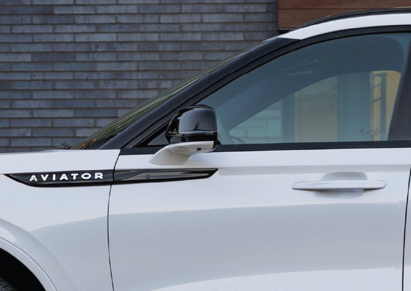 The driver’s side door and fender badging of a white 2026 Lincoln Aviator® SUV are showcased. | Mathews Lincoln in Marion OH