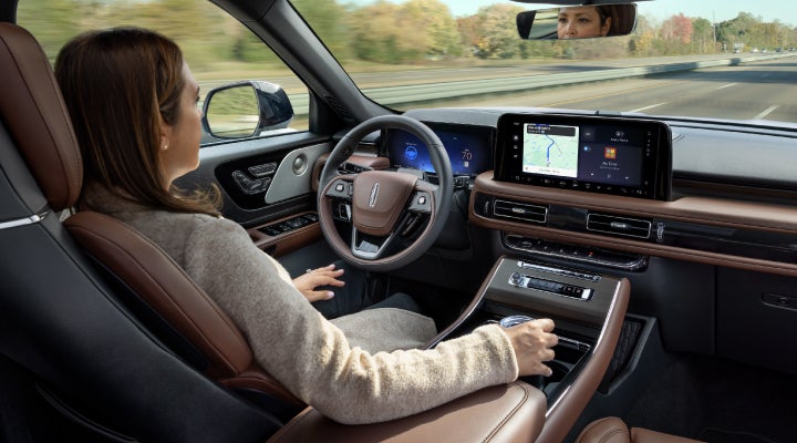 A 2026 Lincoln Aviator® SUV is being driven hands-free on a highway near a forest | Mathews Lincoln in Marion OH